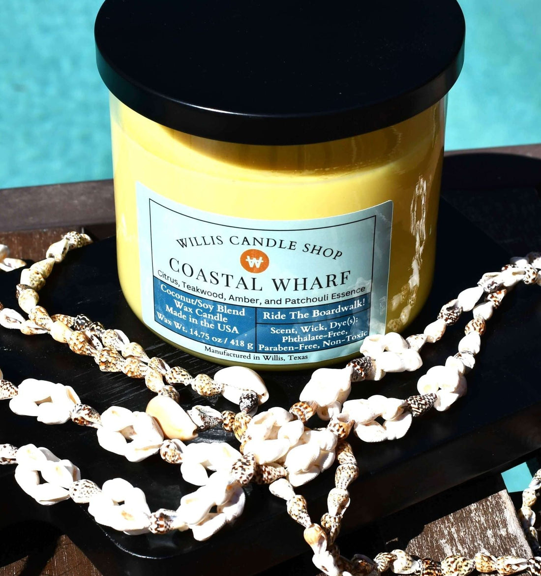 3 wick candle as scented candle in pool area with sea shell necklace.