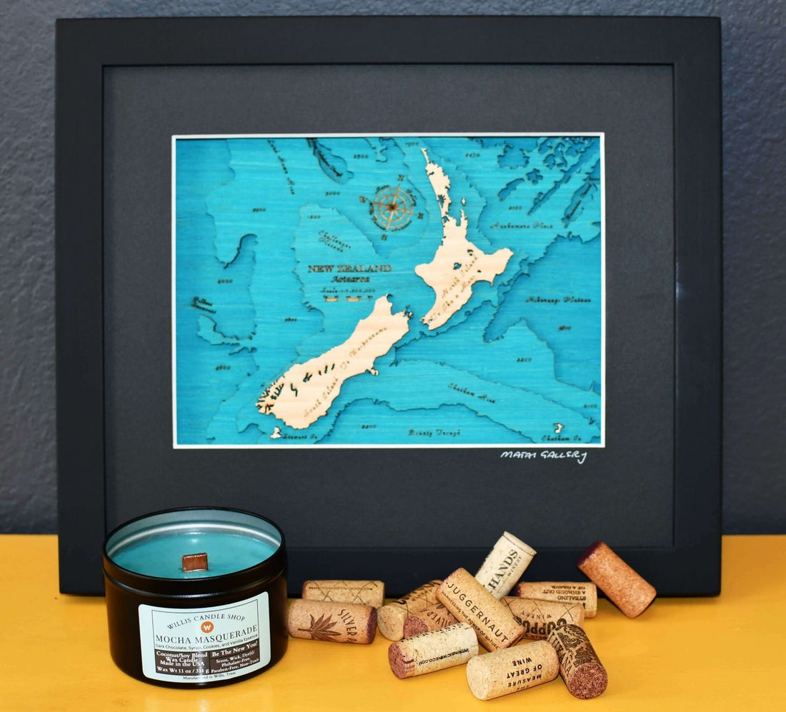 Black tin candle on a sofa table with corks and a picture of New Zealand.