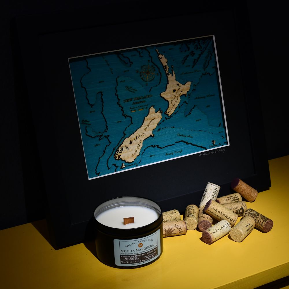 Wood wick candle in the shadows on the yellow sofa table with corks and a picture.
