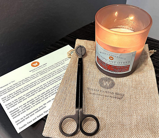 Scented candle burning next to candle care instruction card.