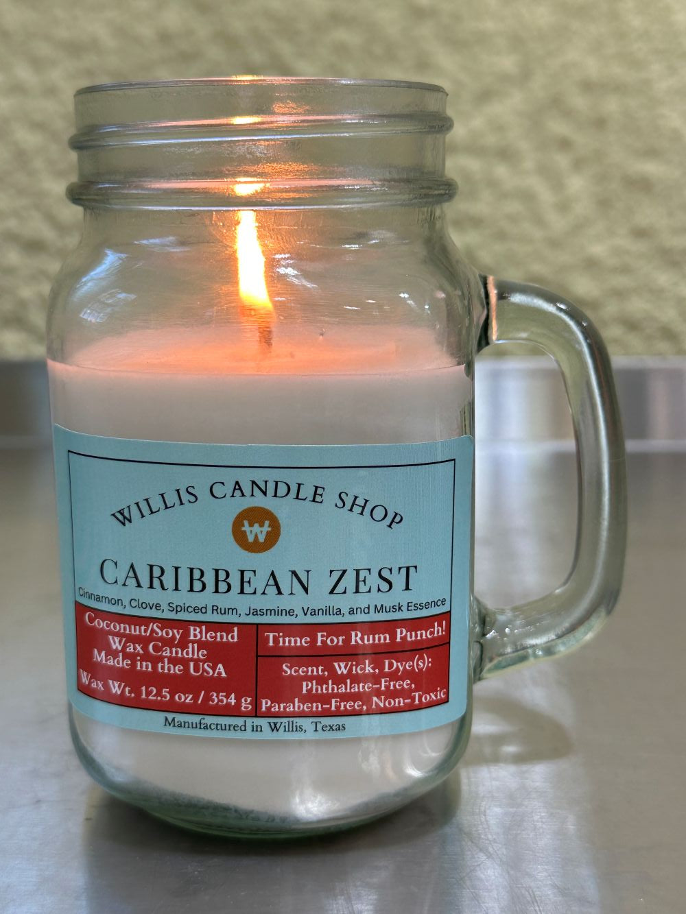 Caribbean Zest candle burning on a table at the Willis Candle Shop.