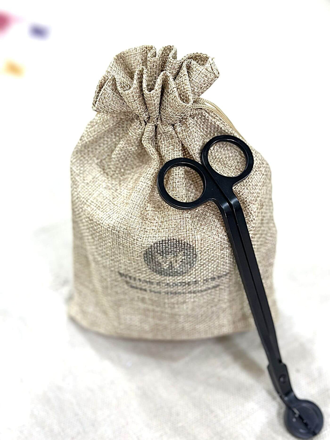 Scented candle in a burlap bag with wick trimmers.
