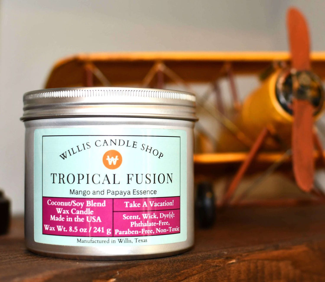 Silver tin candle with Tropical Fusion fragrance and model airplane in background.