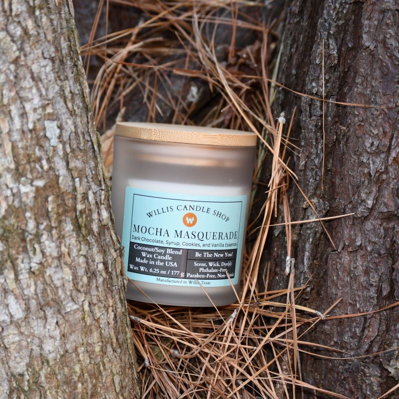 White frosted glass candle with bamboo lid in the forest of Willis, Texas.