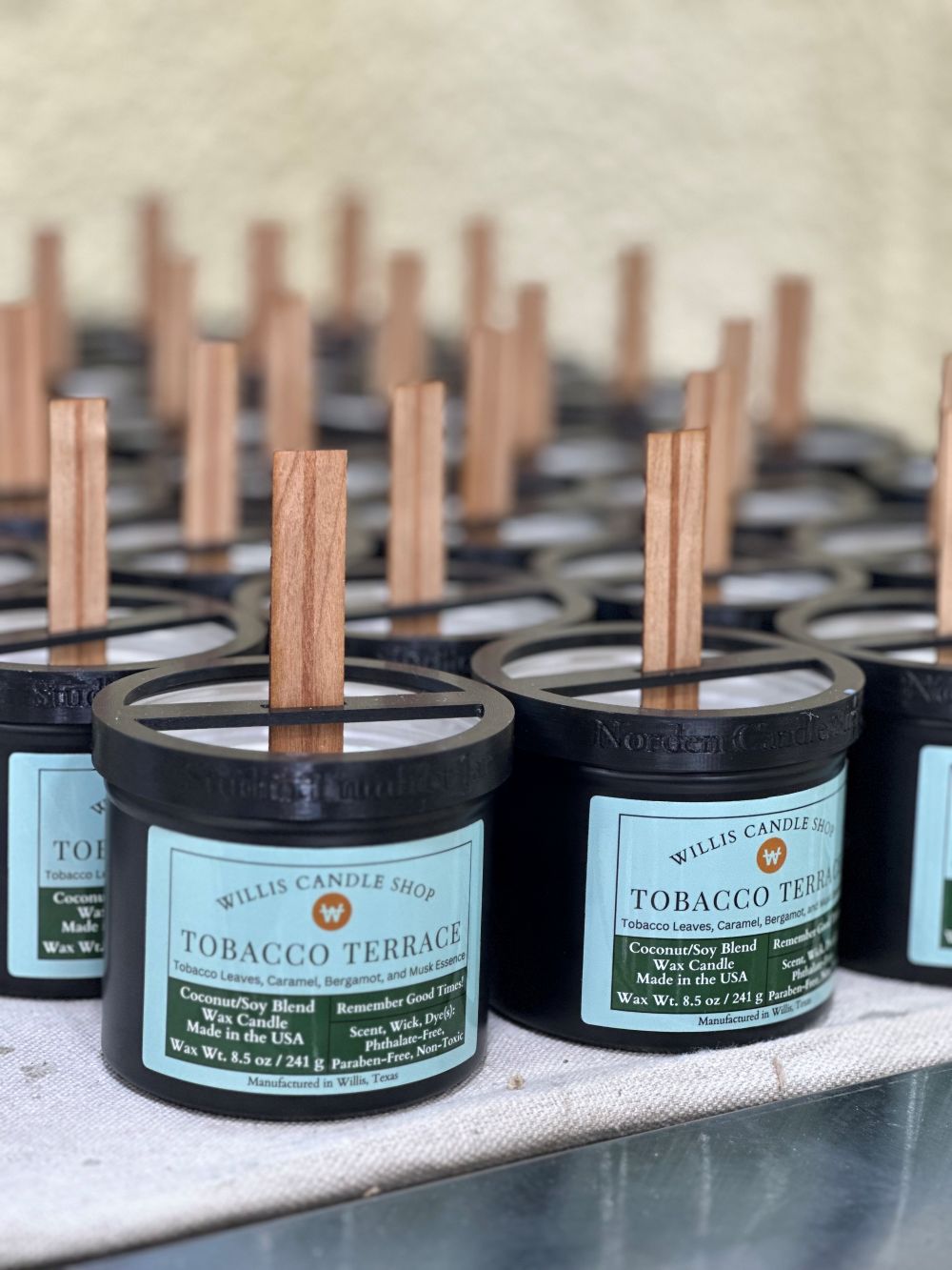 Tobacco candle production with wooden wick candle option in black tins.