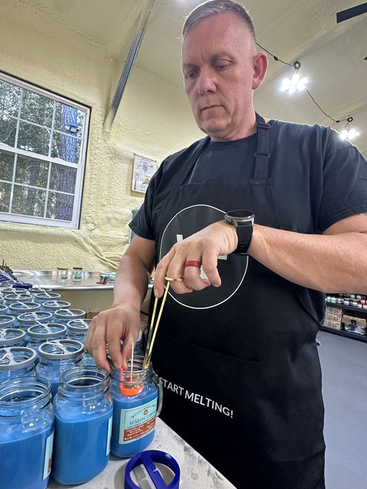 Rob Woloszyn trimming wicks on the Sunrise Coffee candle with blue wax at the Willis Candle Shop.