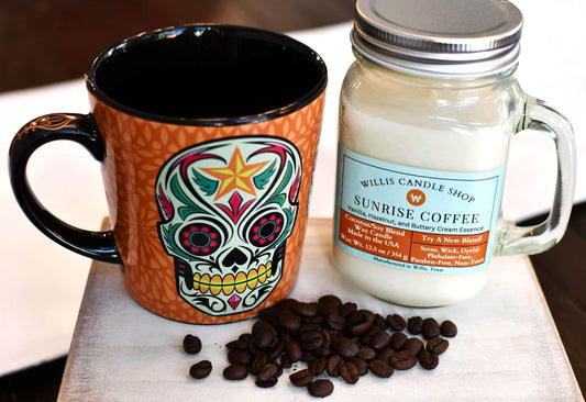 Sunrise Coffee candle with mug and coffee beans on a table.