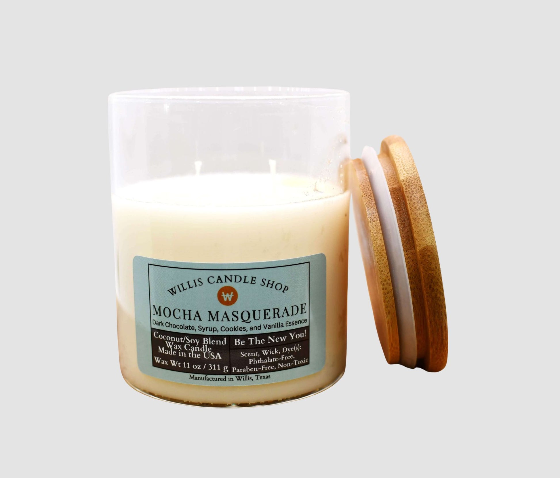 Candle with a wooden lid labeled 'Mocha Masquerade' from Willis Candle Shop on a light gray background.