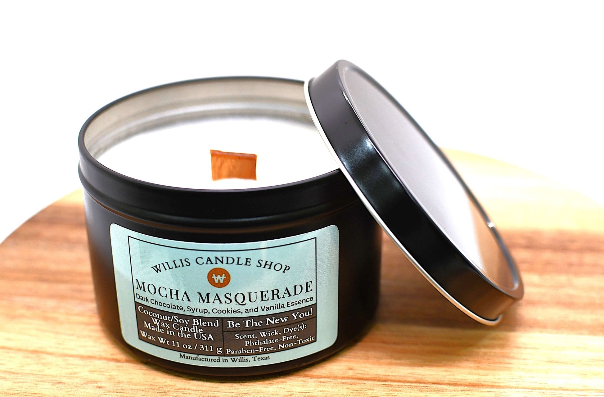 Candle in a tin with a label on a wooden surface and wood wick.