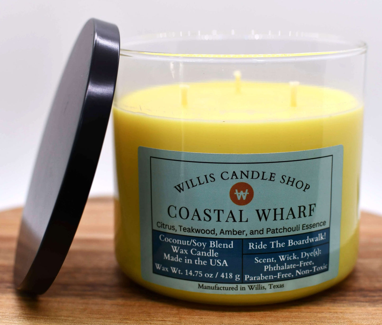 Yellow coconut and soy 25/75 blended candle in a jumbo glass container with black lid and Coastal Wharf fragrance.